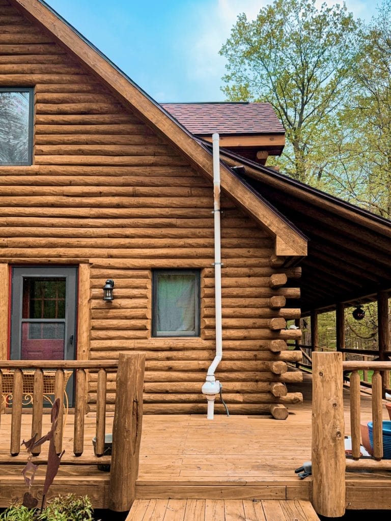 Wooden cabin with radon mitigation system installed on exterior wall
